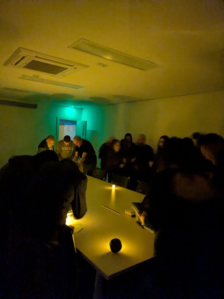 Persones jugant a l'scape room de l'Apagada general en una sala fosca il·luminada per espelmes.