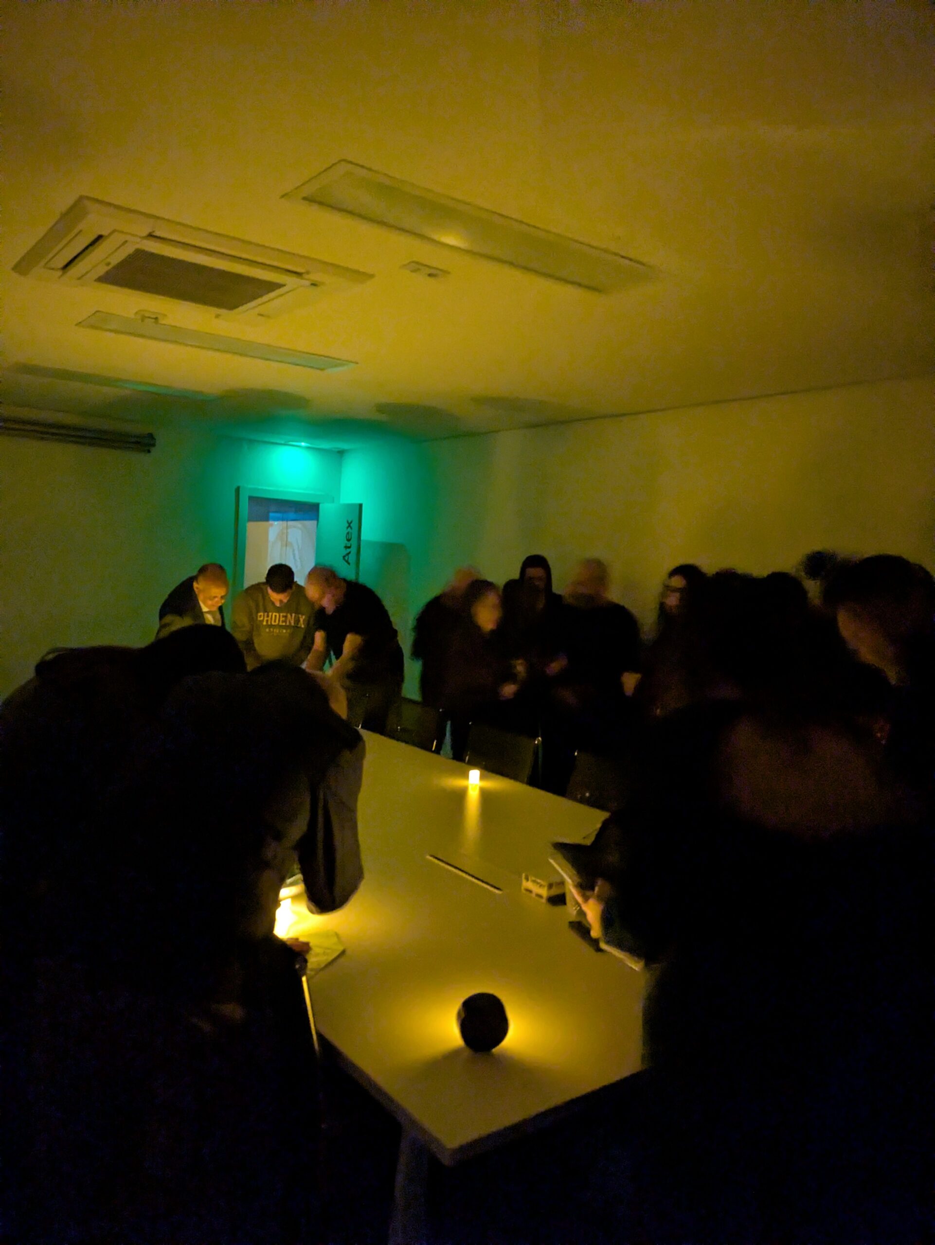 Persones jugant a l'scape room de l'Apagada general en una sala fosca il·luminada per espelmes.